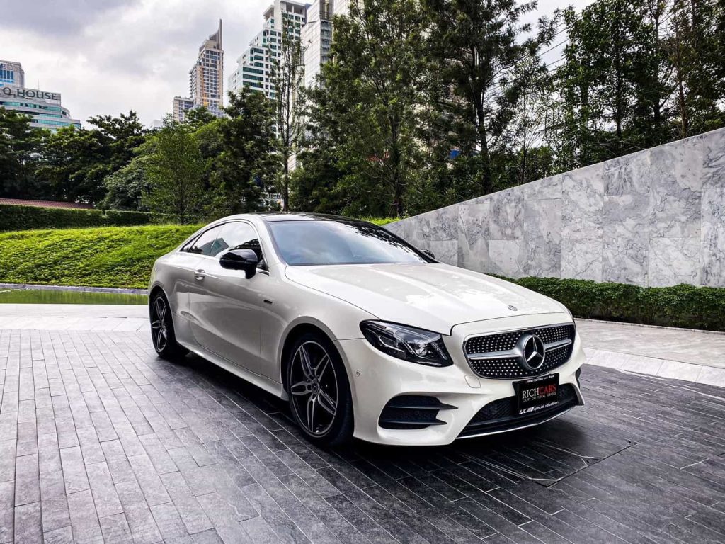 Starting at 16,000 Baht/1 Day

**Indulge in Luxury: Mercedes-Benz E-Class Coupe 300e 2019**

Renting a Benz guarantees a premium experience, and the Mercedes-Benz E-Class Coupe 300e 2019 lives up to the reputation. Boasting a beautiful and modern design, a powerful yet fuel-efficient engine, cutting-edge technology, and a luxurious interior, it caters to those seeking value for their money and an outstanding driving experience.

*E-Class Coupe 300e 2019 Highlights:*
- **Engine Performance:** Powered by a 2.0-liter 4-cylinder gasoline engine working in tandem with an electric motor, the E-Class Coupe 300e 2019 delivers a maximum power of 255 horsepower and a peak torque of 370 Newton-meters. It achieves a top speed of 250 kilometers per hour, with a fuel consumption rate averaging 14.2 kilometers per liter.

- **All-Wheel Drive:** Featuring a 4MATIC all-wheel-drive system paired with a 9-speed automatic transmission, the E-Class Coupe 300e 2019 ensures a responsive and dynamic driving experience. The AMG Line, both inside and out, adds sportiness and sophistication.

- **Luxurious Interior:** The interior is adorned with genuine leather upholstery, power-adjustable front seats with memory function for the driver, an intuitive Head-Up Display, automatic 4-zone climate control, and a Burmester 3D Surround Sound System.

- **Advanced Features:** Advanced driving features include adaptive cruise control, electrically controlled steering wheel, automatic variable-ratio control system, and a Head-Up Display providing essential driving information.

*Price and Availability:*
The E-Class Coupe 300e 2019 is available at a starting price of 3,990,000 Baht, making it a car that offers great value. With excellent performance, fuel efficiency, and advanced technology, it suits those in search of a premium car.

*Pros and Cons:*
**Pros:**
- Modern and luxurious design
- Excellent performance
- Fuel-efficient
- Cutting-edge technology
- Luxurious and comfortable interior

**Cons:**
- Relatively high price
- Limited rear seating space
- Moderate cargo space

Overall, the Mercedes-Benz E-Class Coupe 300e 2019 is an outstanding car, delivering value for its price, exceptional performance, fuel efficiency, and advanced technology—ideal for those seeking a premium driving experience.